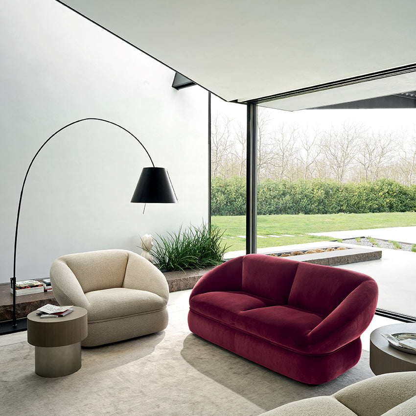 Modern living room with a red sofa, beige armchair, and floor lamp.