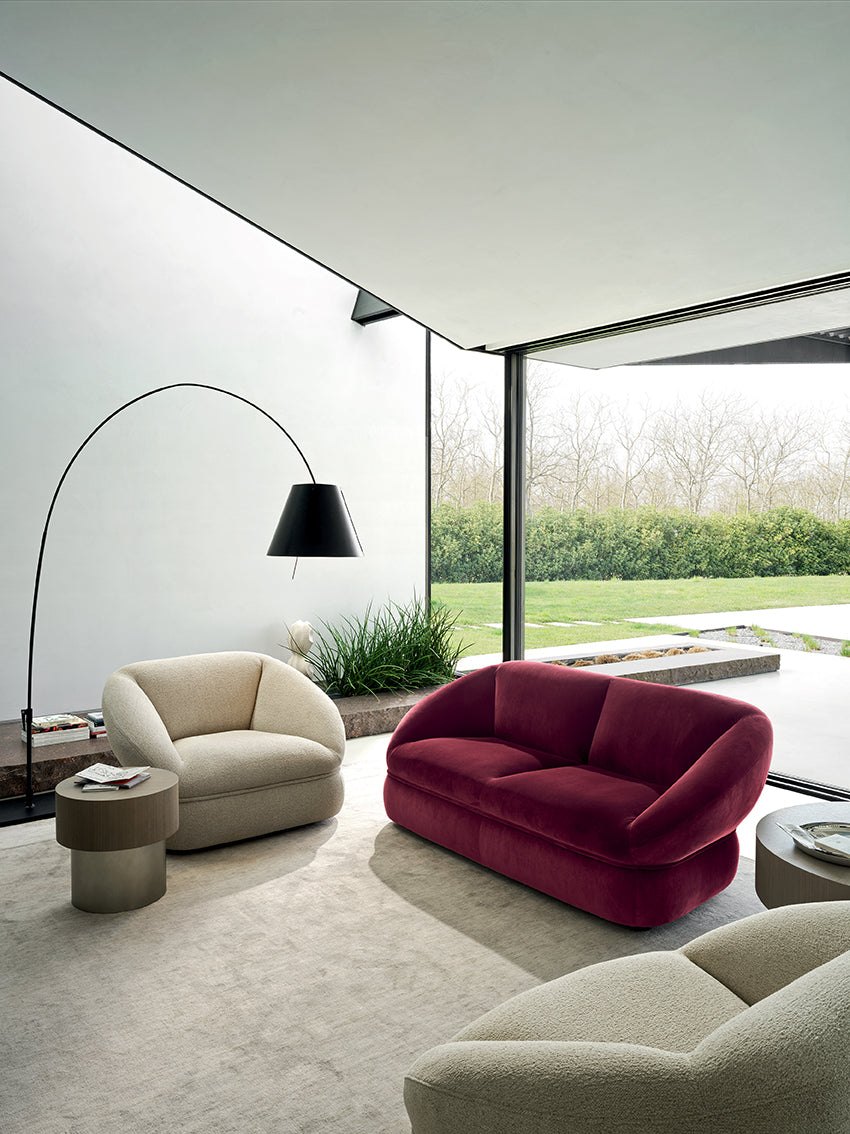 Modern living room with a red sofa, beige armchair, and floor lamp.