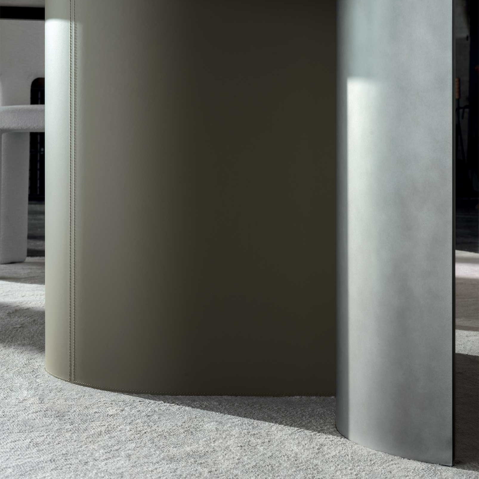 Close-up of a modern, curved concrete wall with a textured floor.