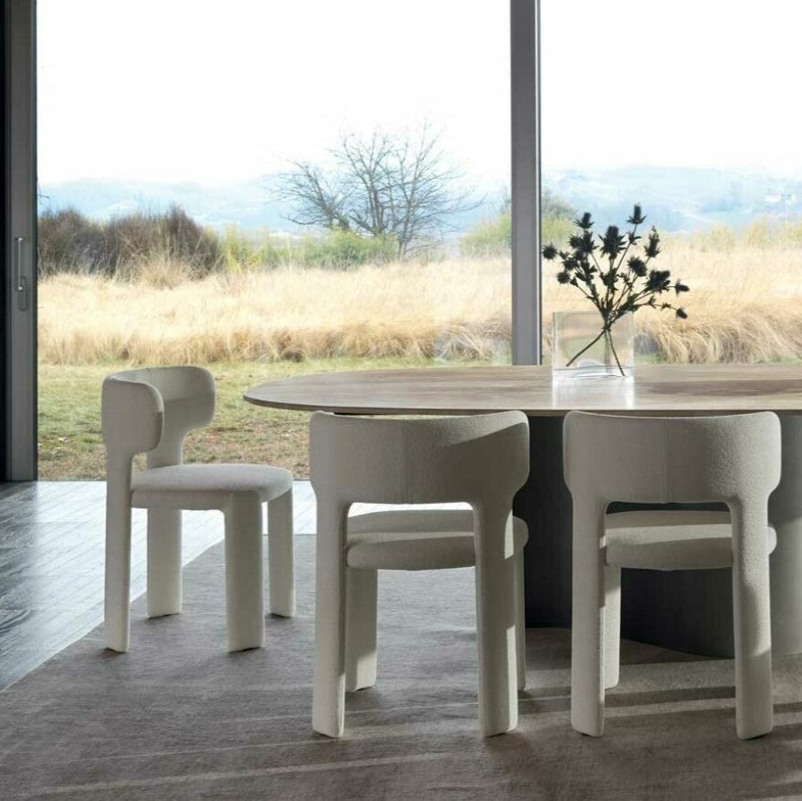 Modern dining room with a round table and chairs in front of large windows with a scenic view.