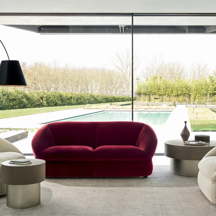 Modern living room with a red sofa, beige chairs, and a floor lamp.