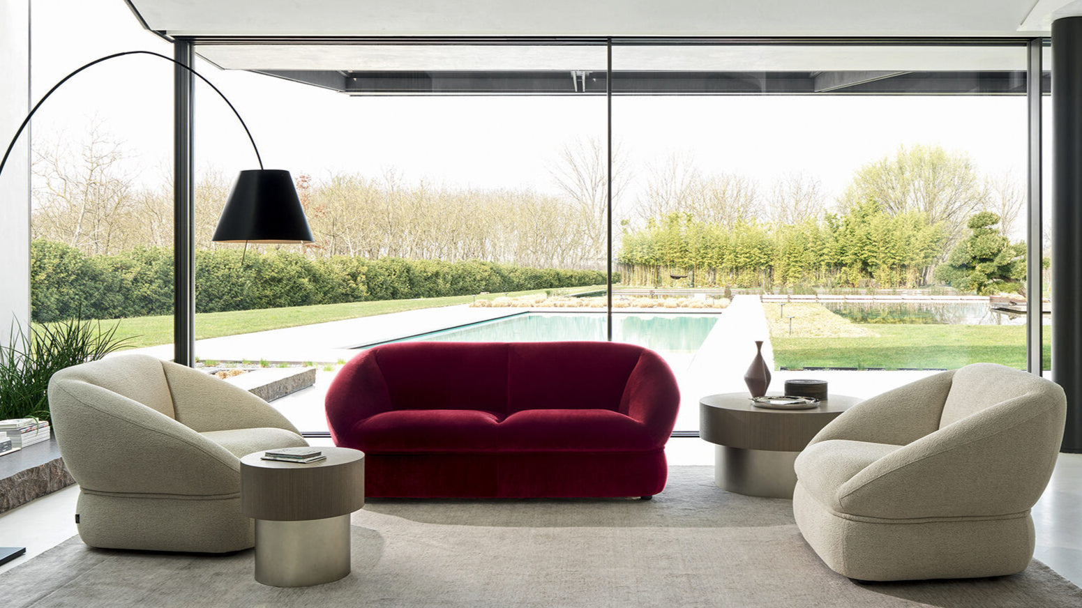 Modern living room with a red sofa, beige chairs, and a floor lamp.
