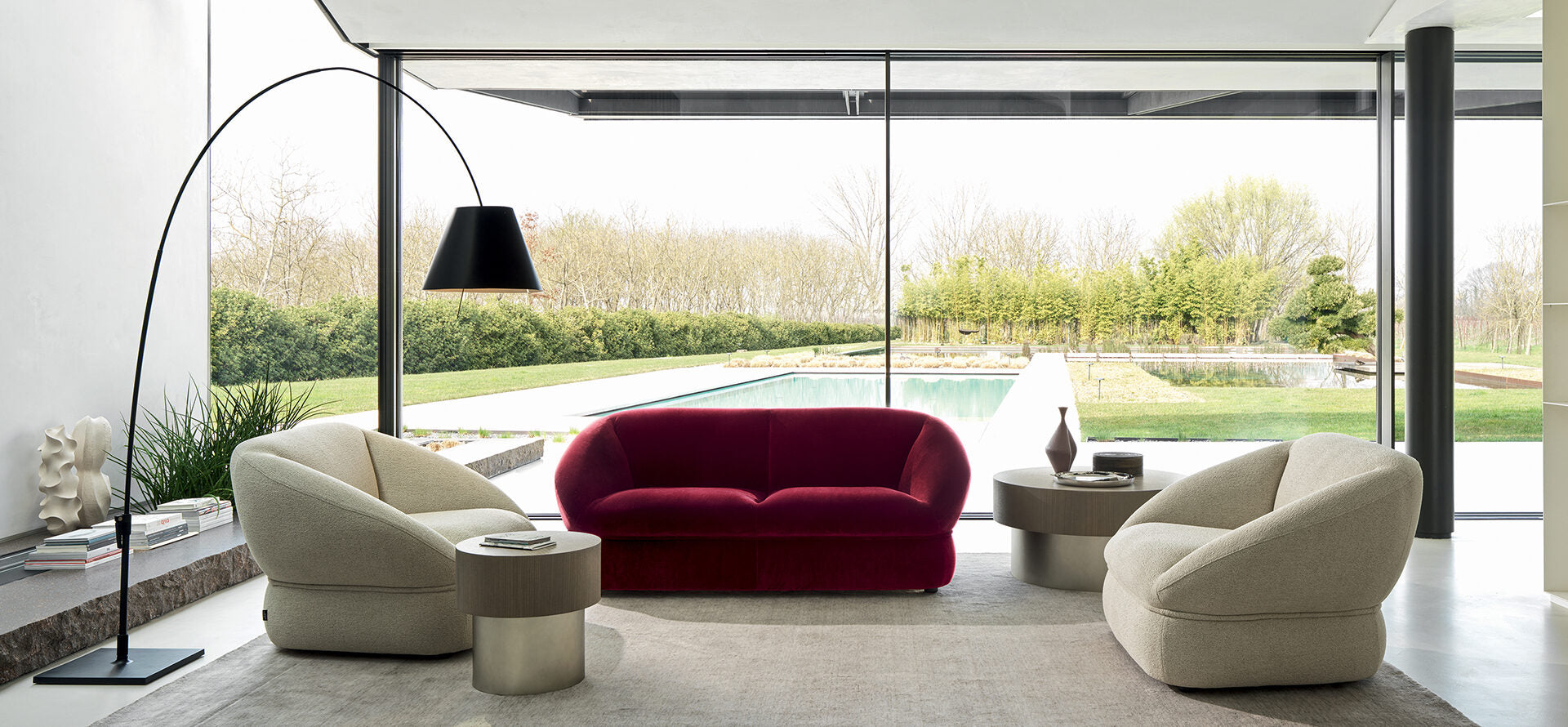 Modern living room with a red sofa, beige chairs, and a floor lamp.