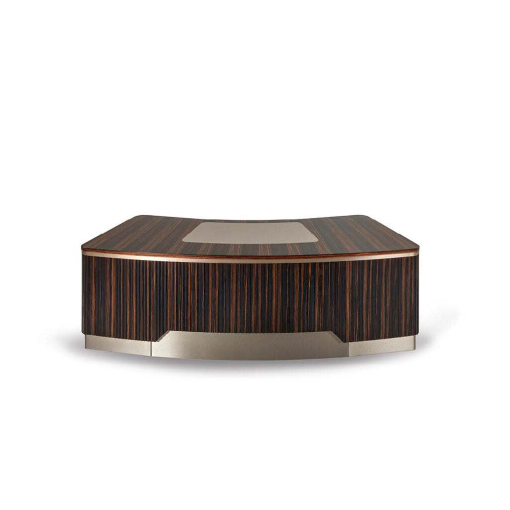 A curved presidential desk with a ribbed satined Makassar Ebony veneer finish and a leather pad on top. The desk has drawers with velvet fabric lining and stainless steel details.