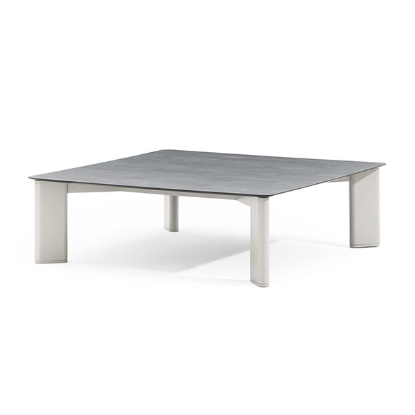 A rectangular coffee table with a gray, bush-hammered ceramic top and powder coated aluminum structure, featuring elliptical legs.